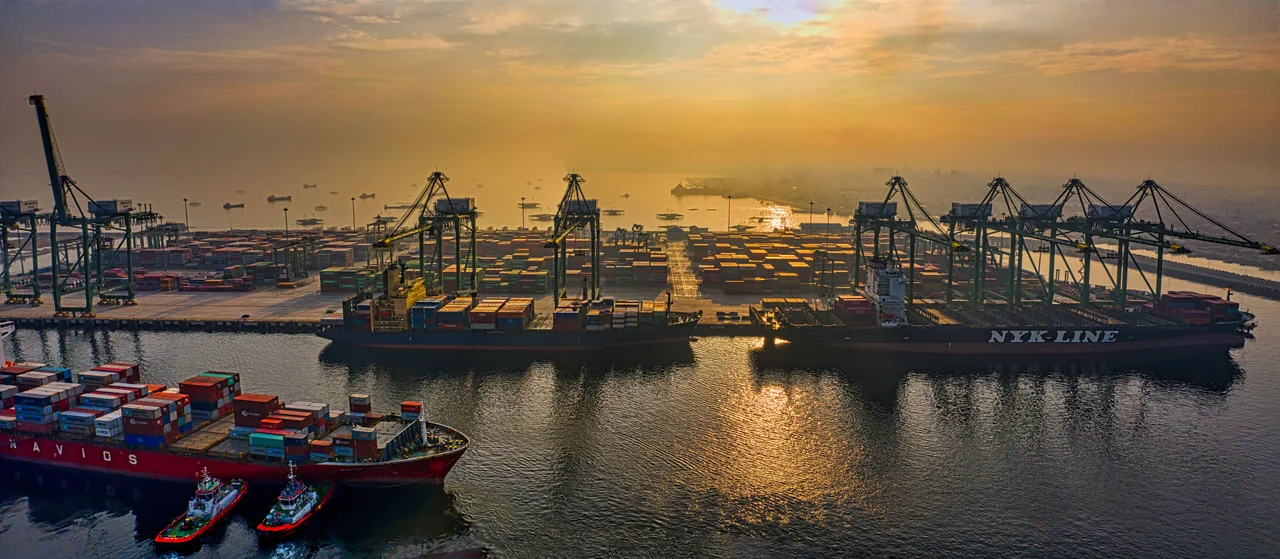 Terminal portuário de contêineres e navios ao entardecer